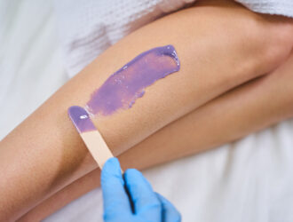 Professional depilation. Competent cosmetologist wearing rubber gloves while doing procedure in salon