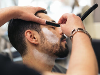 Young Bearded Man Getting Beard Haircut With A Razor By Barber. Barbershop Theme